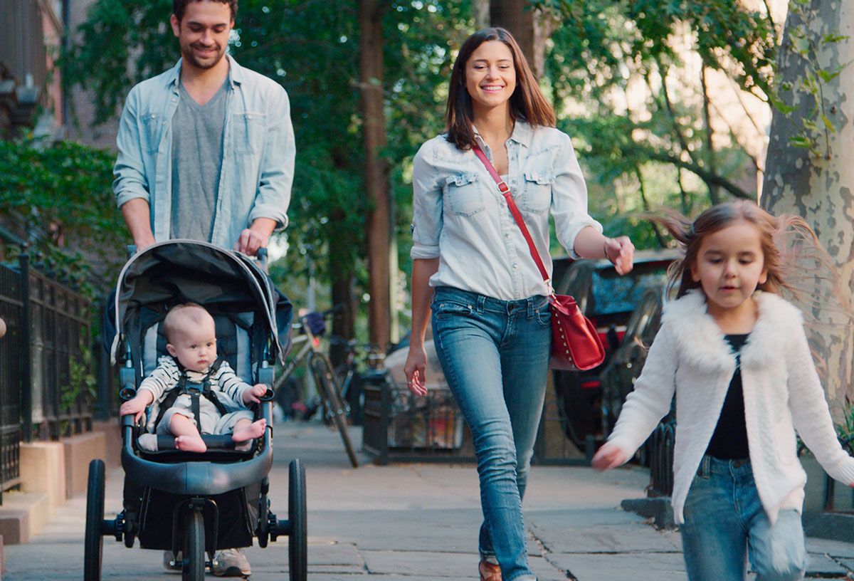Family Day Out With Dad Pushing Baby In Buggy As They Walk Along Urban Street In Philadelphia, PA