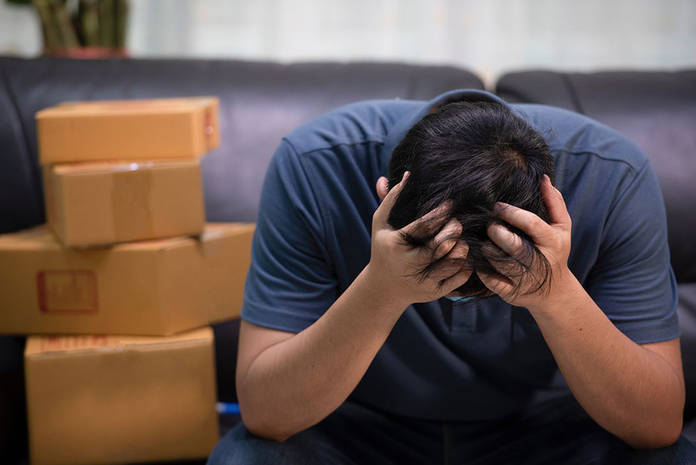A man leaning down with his head in his hands while realizing several mistakes he made during his move in Philadelphia, PA